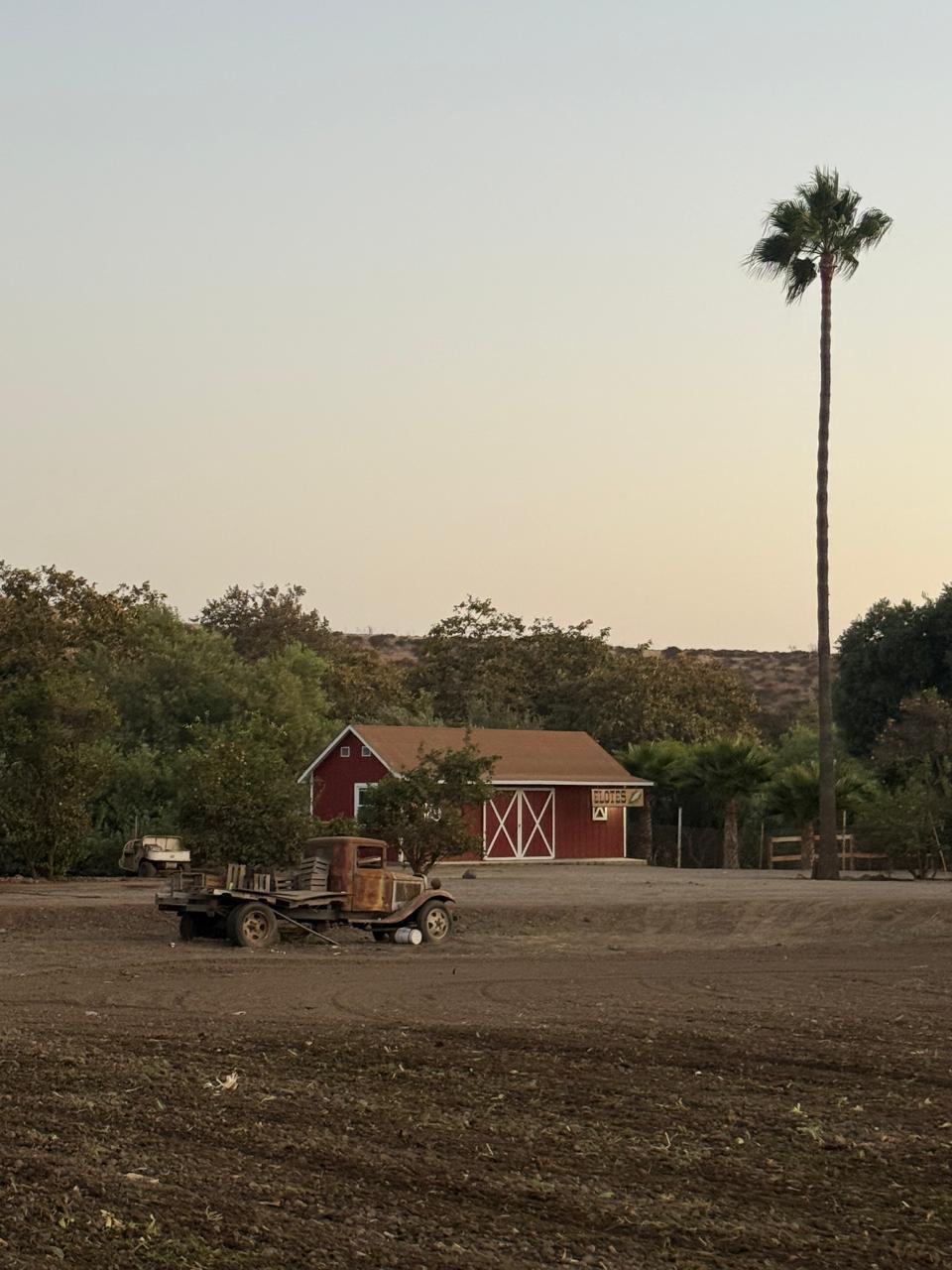 Troje roja del rancho con camión antiguo al atardecer